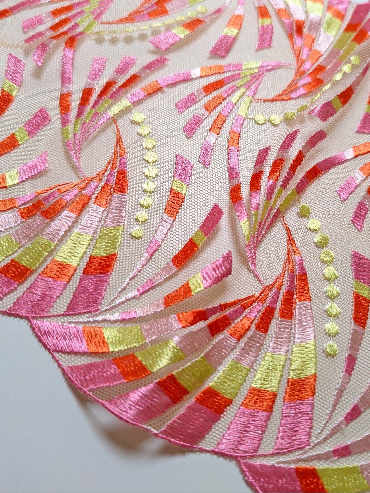 EMBROIDERY WITH SCALLOPED EDGE AND BOLD FAN DESIGN WITH PINK, ORANGES AND LIME PRINTED YARNS ON SHEER TULLE BASE.